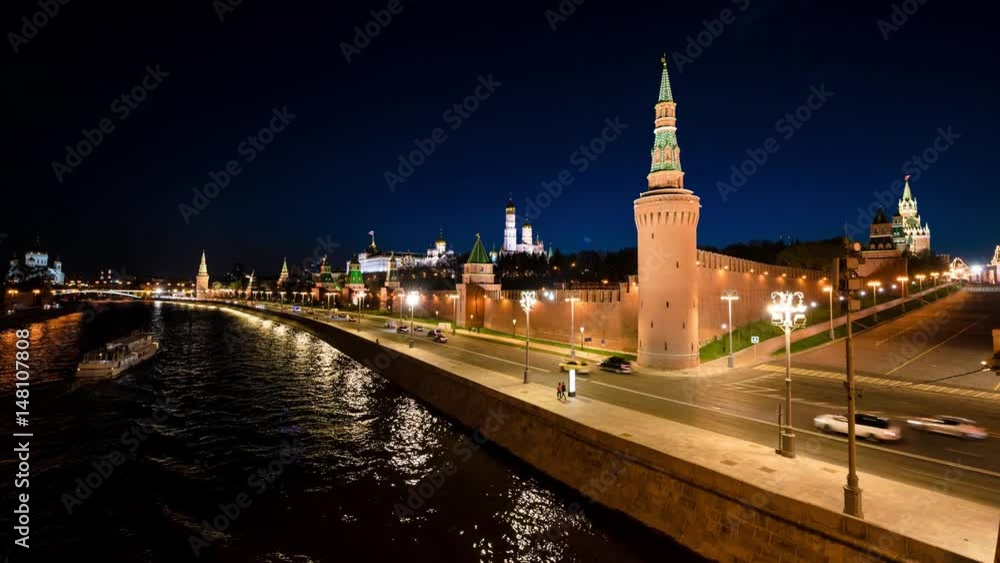 Time-lapse. Aerial view of Kremlin at night in Moscow, Russia. Touristic boats moving down the river, car traffic at the road. Popular place. View from the bridge.