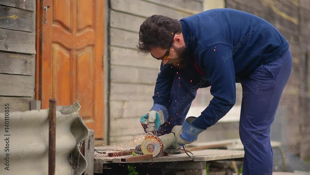 Worker with a beard and in yellow goggles saws the pipe with an abrasive machine Worker with a beard and in yellow goggles saws the pipe with an abrasive machine