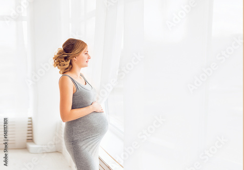 Young beautiful pregnant woman standing near window at home Free Download Young beautiful pregnant woman standing near window at home - GFXLoad
