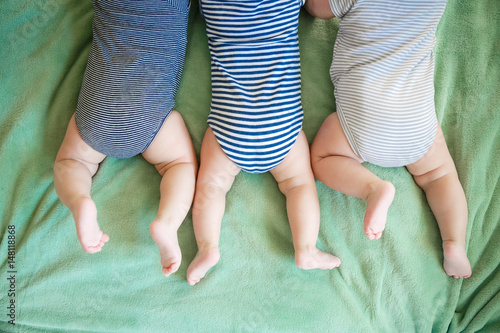 Foto Newborn triplets lie on a stomach on a blanket