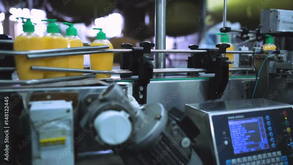Packaging machine / process of packaging liquid soap in a modern factory / Line of packaging at a cosmetic plant / Plastic containers on a packaging line at a cosmetic factory / Industrial equipment Packaging machine / process of packaging liquid soap in a modern factory / Line of packaging at a cosmetic plant / Plastic containers on a packaging line at a cosmetic factory / Industrial equipment