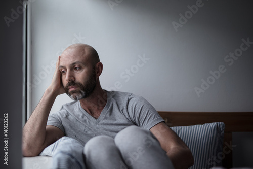 Mid forties depressed man in bed at home photo