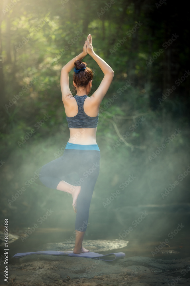 Fototapeta premium YOGA Backside young woman practicing yoga and relaxing in forest of natural.