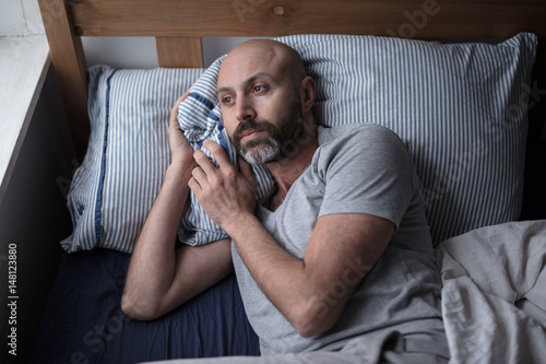 Mid forties depressed man in bed at home photo