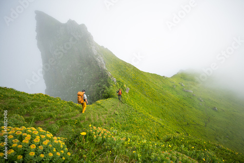 Two people hiking by hazy green mountain side, Iceland, Europe  photo