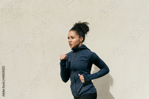 Side view of female athlete running against wall © Artem Varnitsin