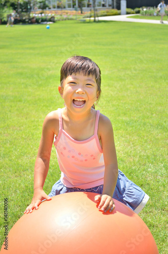 芝生広場でボール遊びをする女の子（夏）