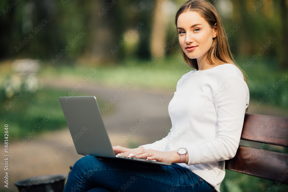 Happy student teenager girl learning with a laptop lying in a bench in an university campus Happy student teenager girl learning with a laptop lying in a bench in an university campus