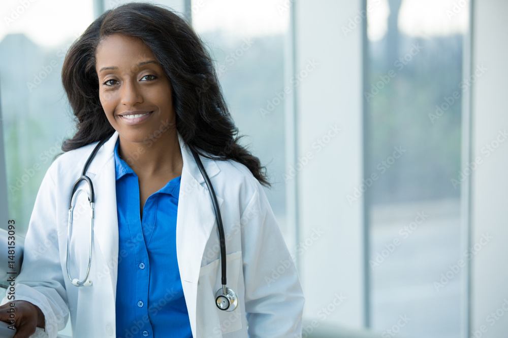 Closeup portrait of friendly, smiling confident female healthcare professional with lab coat, stethoscope, arms crossed. Isolated hospital clinic background. Time for an office visit Closeup portrait of friendly, smiling confident female healthcare professional with lab coat, stethoscope, arms crossed. Isolated hospital clinic background. Time for an office visit