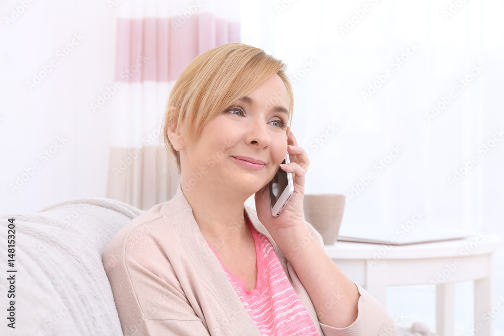 Happy senior woman with phone on couch at home