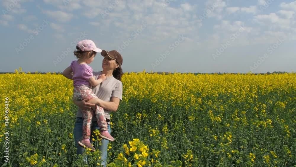 Mother hugging her daughter in nature. Woman with little girl on yellow field. A happy family. Rapeseed field. Mother hugging her daughter in nature. Woman with little girl on yellow field. A happy family. Rapeseed field.