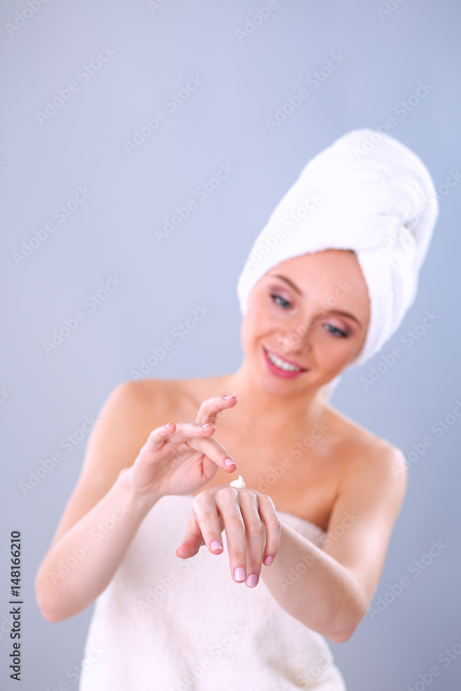 Young woman putting cream on her hand Isolated on gray background Young woman putting cream on her hand Isolated on gray background
