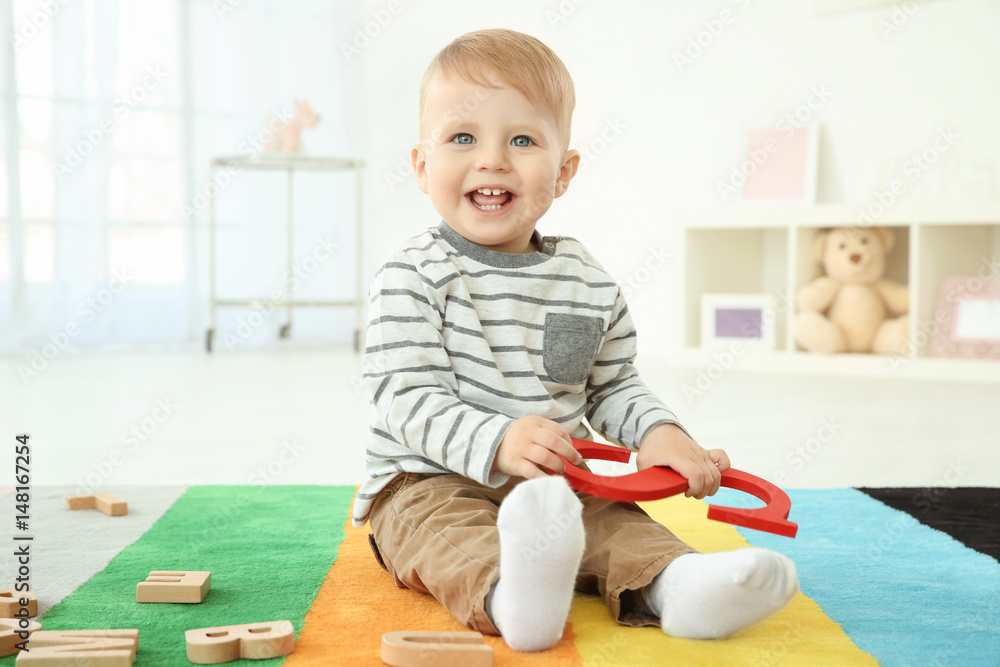 Cute little child with letter S sitting on floor at home Cute little child with letter S sitting on floor at home
