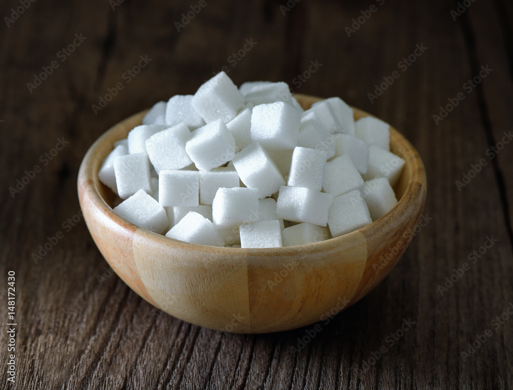 Sugar cubes in wood bowl on wood table Sugar cubes in wood bowl on wood table