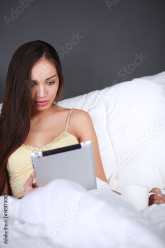 Women use a tablet pc on the bed