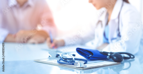 Foto Doctor woman sitting with  male patient at the desk