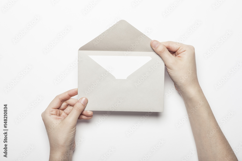 woman hand hold a envelope with post card on the white table.