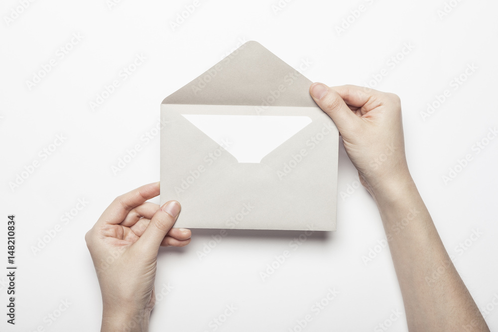 woman hand hold a envelope with post card on the white table. woman hand hold a envelope with post card on the white table.