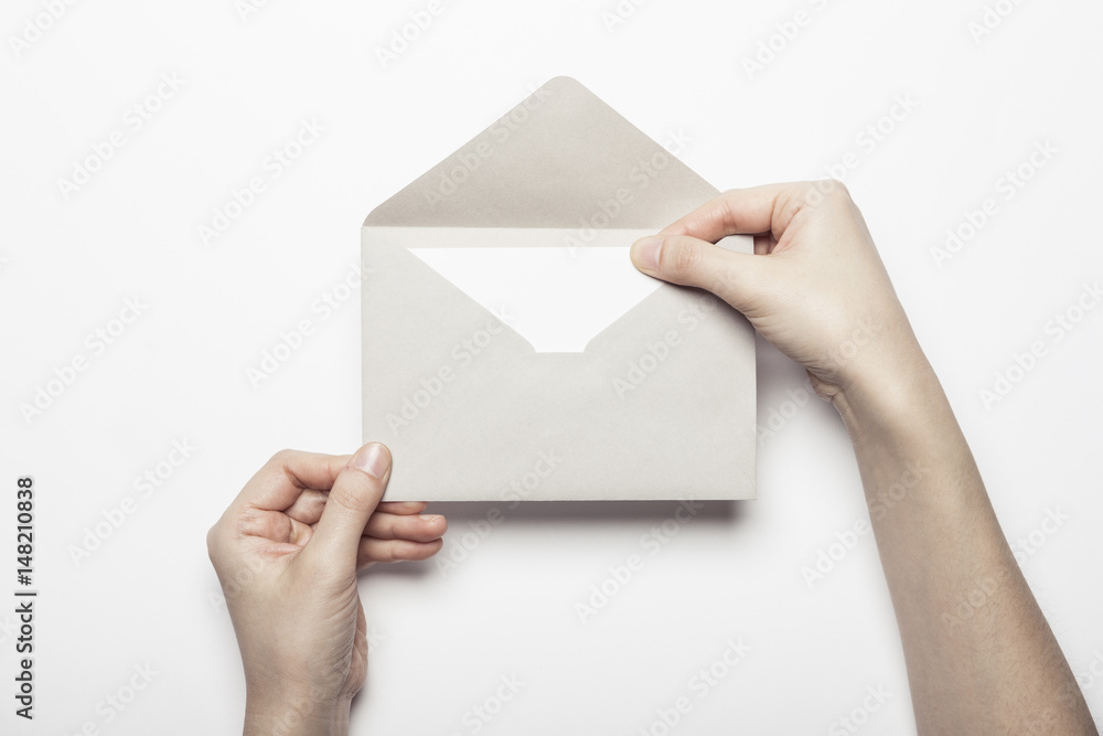 woman hand hold a envelope with post card on the white table. woman hand hold a envelope with post card on the white table.