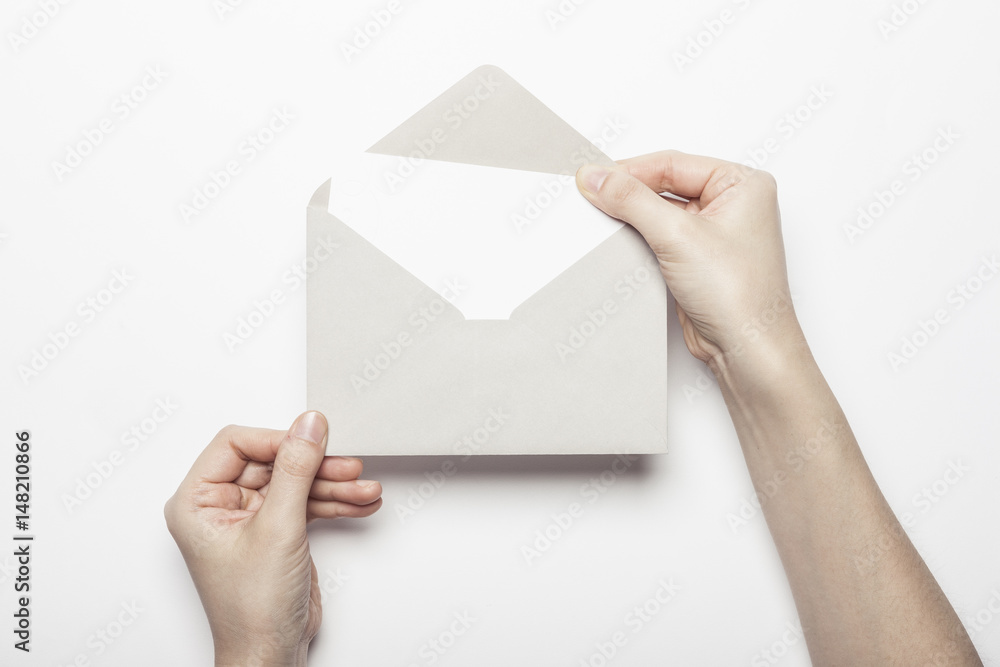 woman hand hold a envelope with post card on the white table.