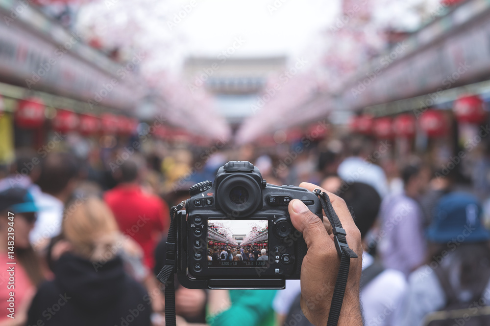 Camera capturing Senso-ji temple walking street (Nakamise) with many tourists in background. - obrazy, fototapety, plakaty 