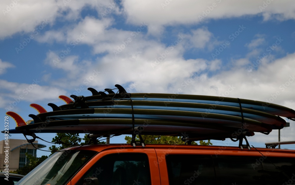 Surf's Up / A stack of surfboards on a car roof.