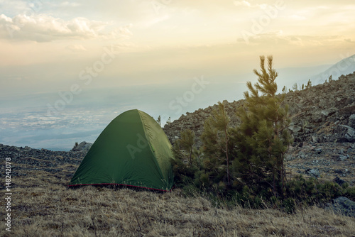 Tent with tourists on the background of the spring landscape view of mountains and the sky at sunset
