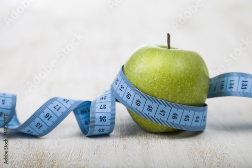 Obraz na płótnie Green apple and measuring tape on a wooden table. w salonie