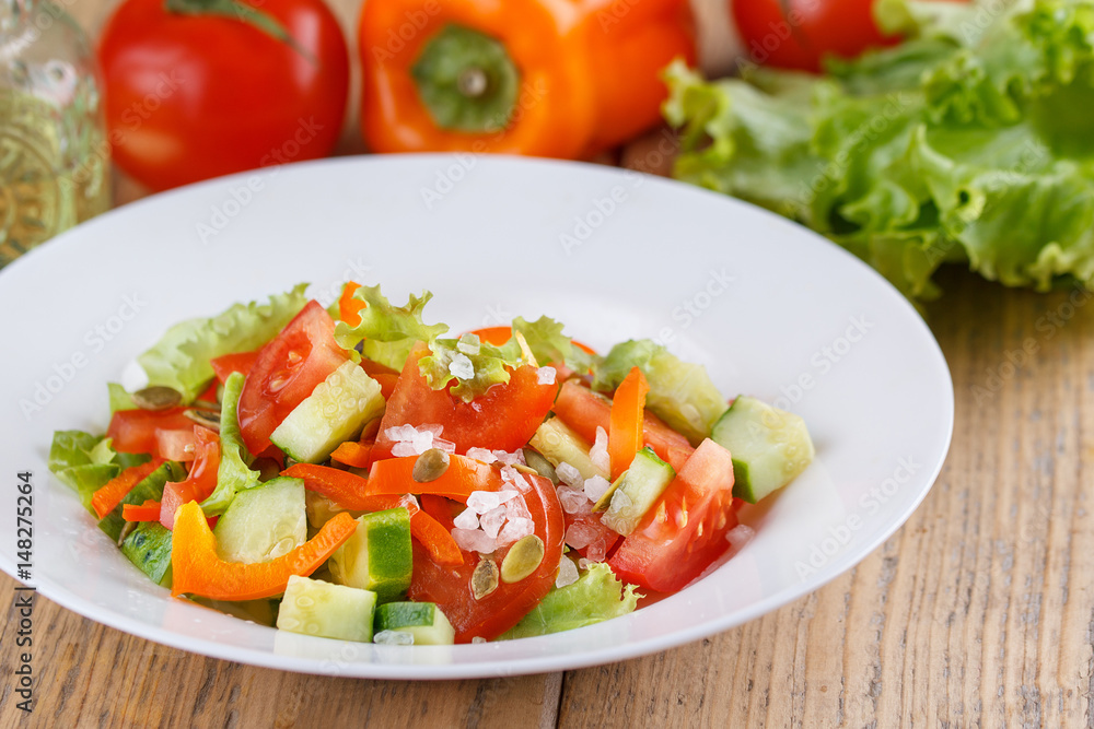 Summer light air salad of fresh vegetables on a wooden background. Still life in a rustic style.