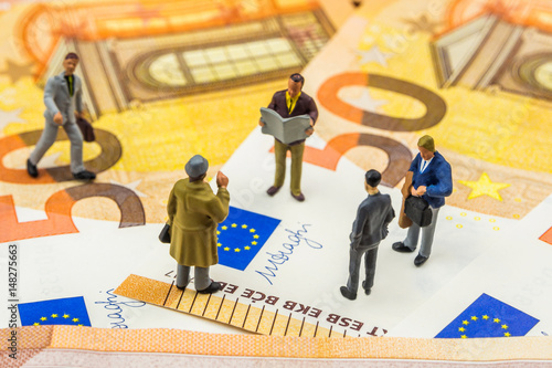 little figurines discussing and standing on new 50 euro banknotes
