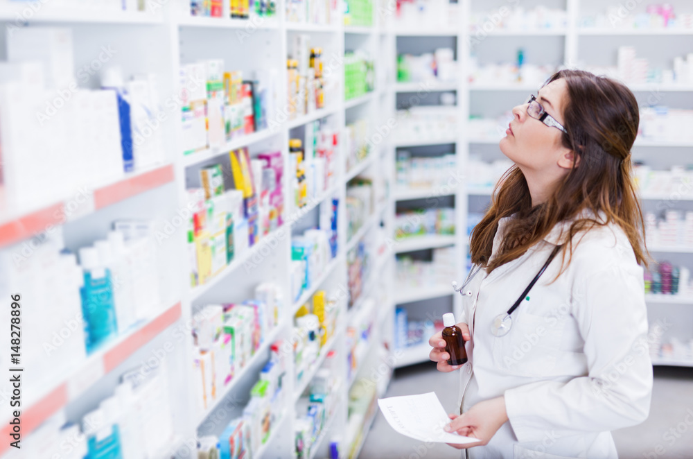 Pharmacist looking and searching for a medication on pharmacy shelf 