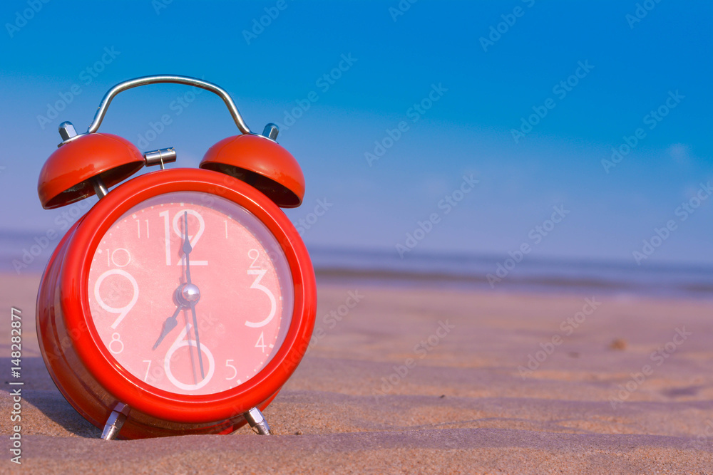 Φωτογραφία closeup of an alarm clock on the sand of a beach adjusting morning  of the summe