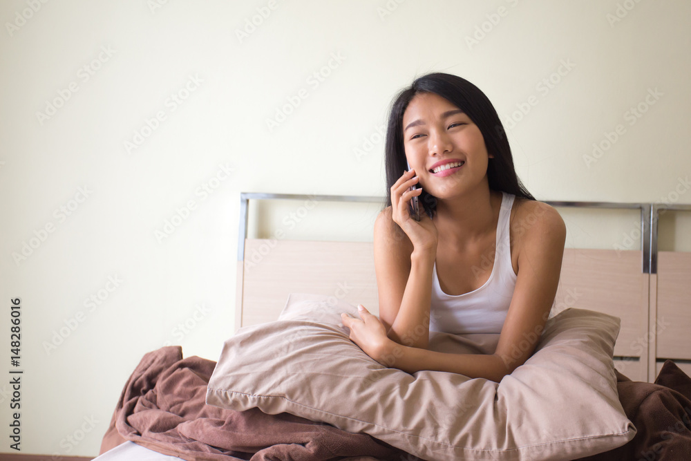 Beautiful asian woman with attractive smile while takling with smart phone, Young woman portrait in bedroom. Beautiful asian woman with attractive smile while takling with smart phone, Young woman portrait in bedroom.