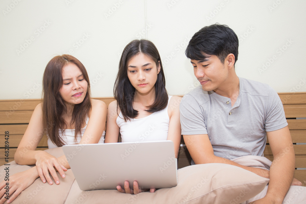 Asian man and woman using computer on bed, Young people portrait in bedroom, 20s-30s age Asian man and woman using computer on bed, Young people portrait in bedroom, 20s-30s age