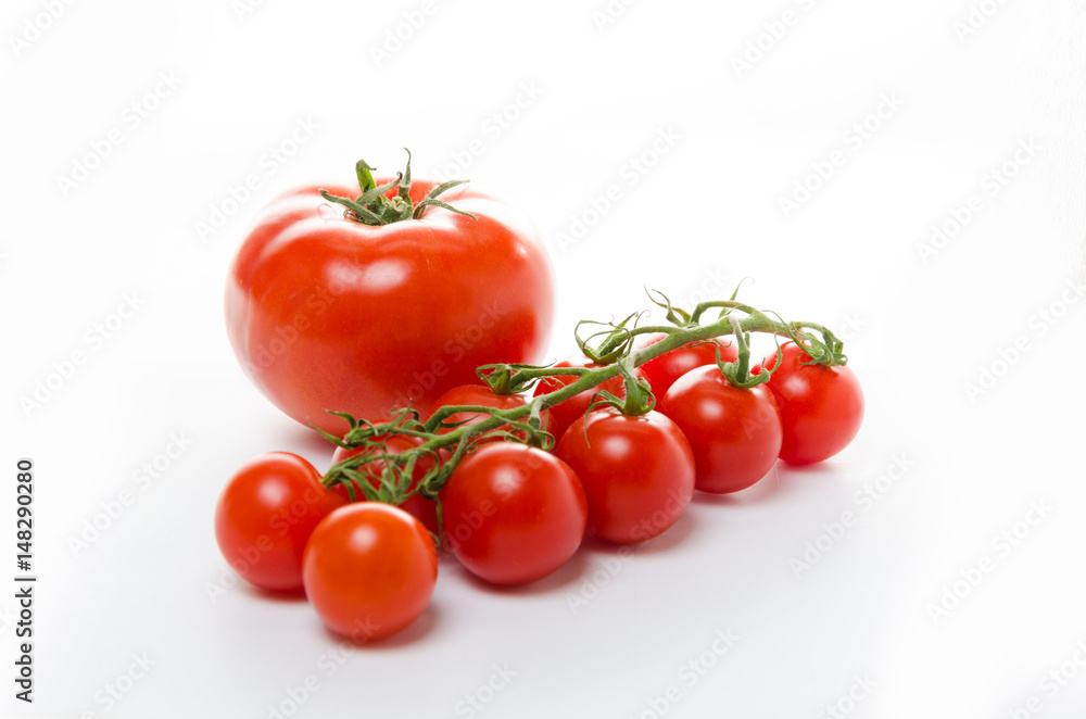 Small cherry tomatoes with green leaves on a white background. Isolated Small cherry tomatoes with green leaves on a white background. Isolated
