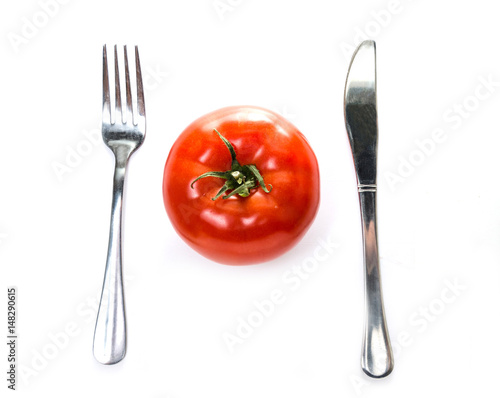 Fork and knife on the sides of a tomato. Isolated