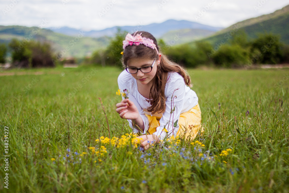 Beautiful blonde girl sitting on a beautiful green grass full of flowers and enjoy while viewing the flowers and says bouquet, sun, nature, pleasure Beautiful blonde girl sitting on a beautiful green grass full of flowers and enjoy while viewing the flowers and says bouquet, sun, nature, pleasure