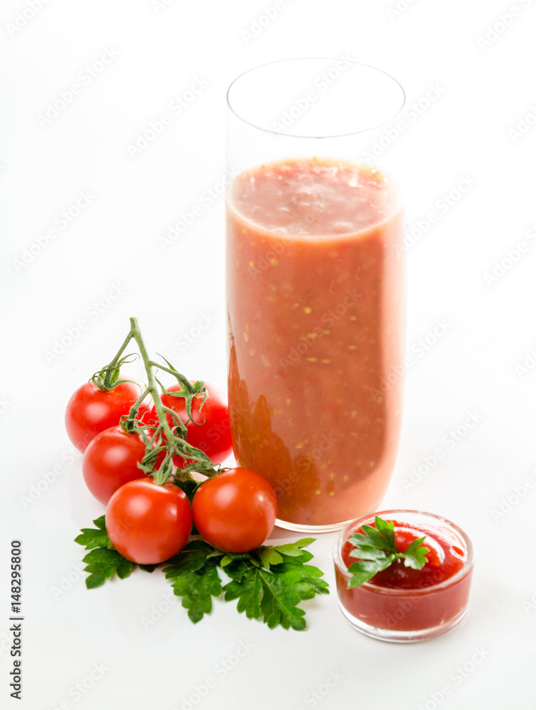 Composition from a tomato and a glass of juice on a white background. Composition from a tomato and a glass of juice on a white background.