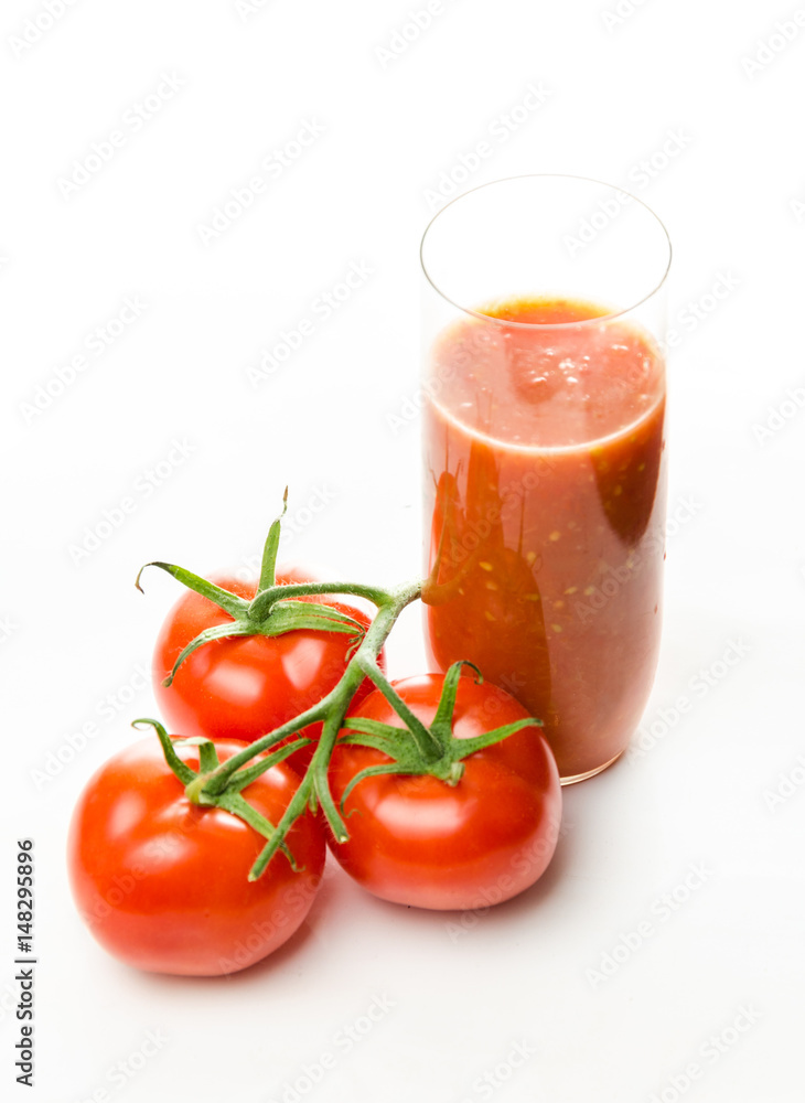 Composition from a tomato and a glass of juice on a white background. Composition from a tomato and a glass of juice on a white background.