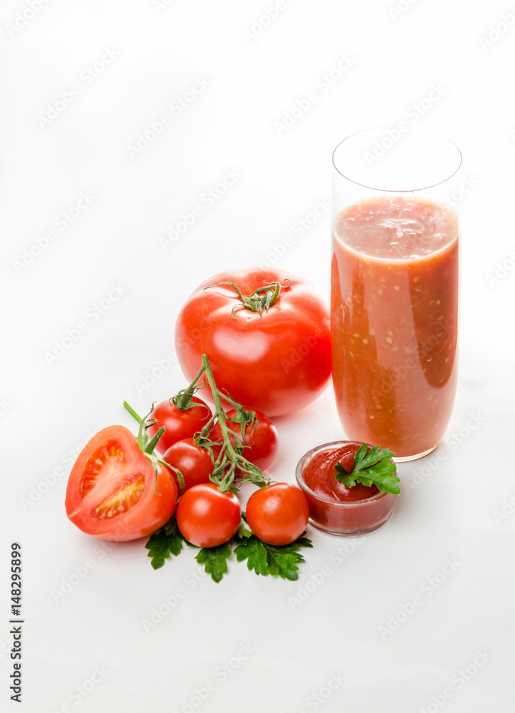 Composition from a tomato and a glass of juice on a white background. Composition from a tomato and a glass of juice on a white background.