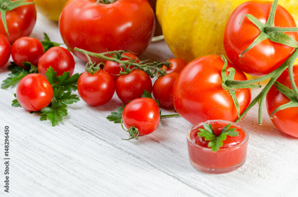 Composition of large tomatoes, cherry, pumpkin, and a glass of juice on a paternal background. Composition of large tomatoes, cherry, pumpkin, and a glass of juice on a paternal background.