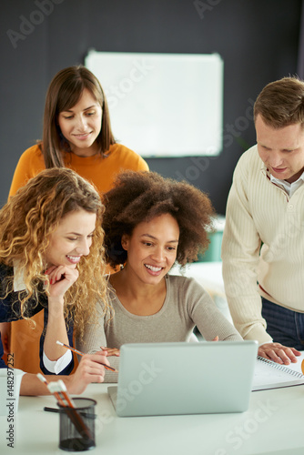 Young people working in modern office, discussing in front of laptop