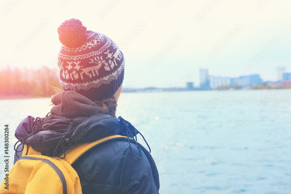 A woman traveler looks out into the distance on a city through a lake. A woman traveler looks out into the distance on a city through a lake.