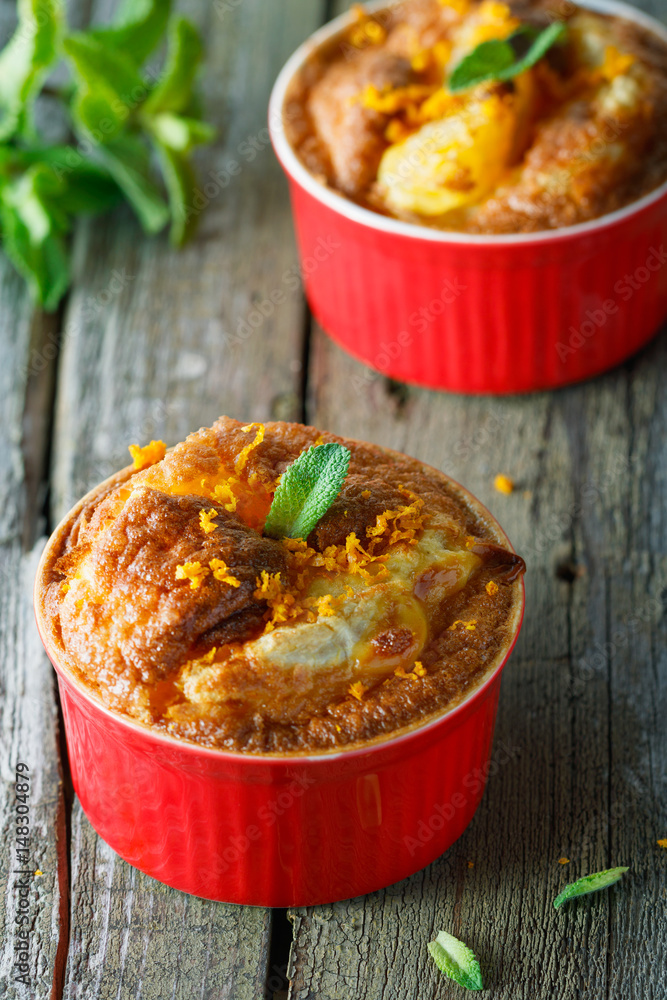 Φωτογραφία Close-up of two baked desserts with orange and mint in red cream-bowls on an old