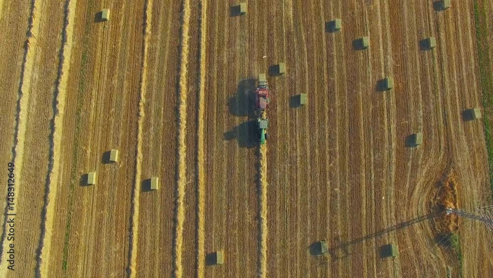 Green tractor with Hay baler producing hay bales in a field - Aerial footage Green tractor with Hay baler producing hay bales in a field - Aerial footage