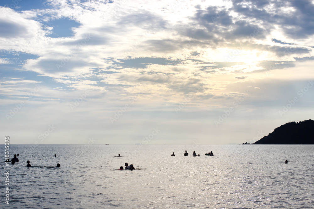 People in the sea with blue sky and sunlight in the evening.