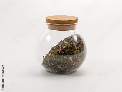 Round glass jar with a cork filled with aromatic tea with dried flowers photo