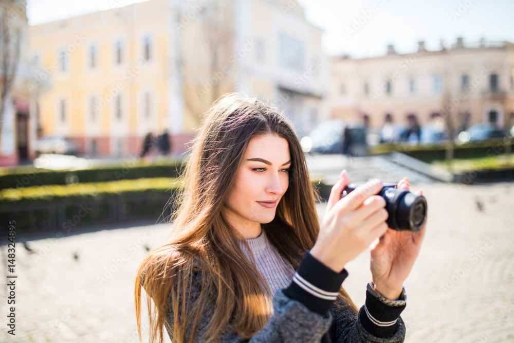 Outdoor smiling lifestyle portrait of pretty young woman having fun in the city in Europe with camera travel photo of photographer making pictures