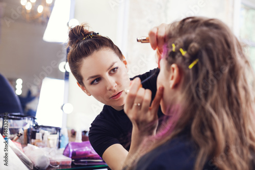 Make-up artist applying mascara on model's eyelashes, selective focus on make up artist photo