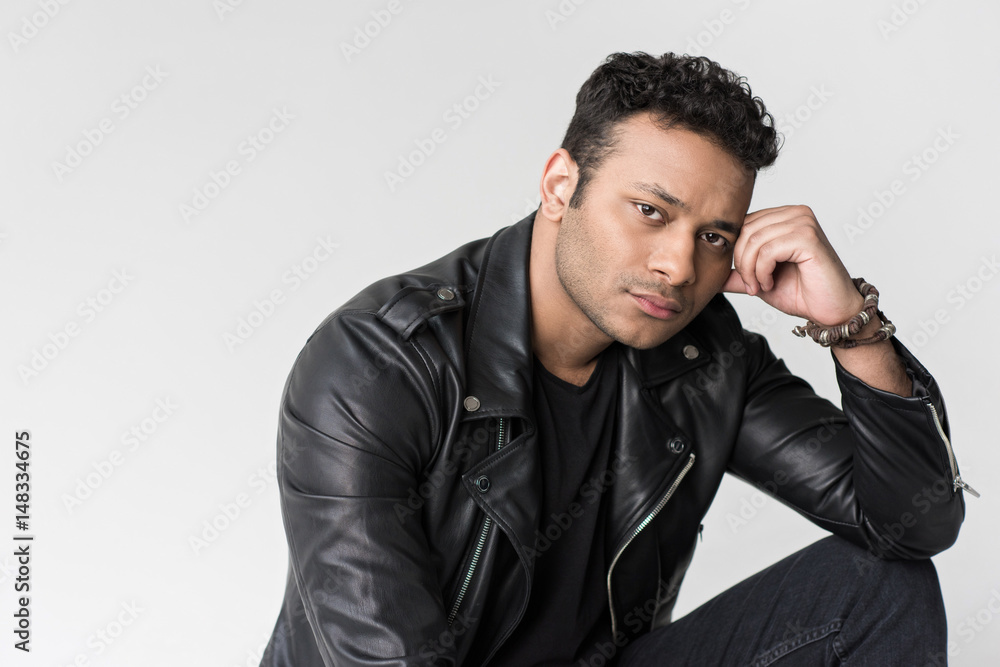 young pensive african american man sitting and looking at camera isolated on grey young pensive african american man sitting and looking at camera isolated on grey